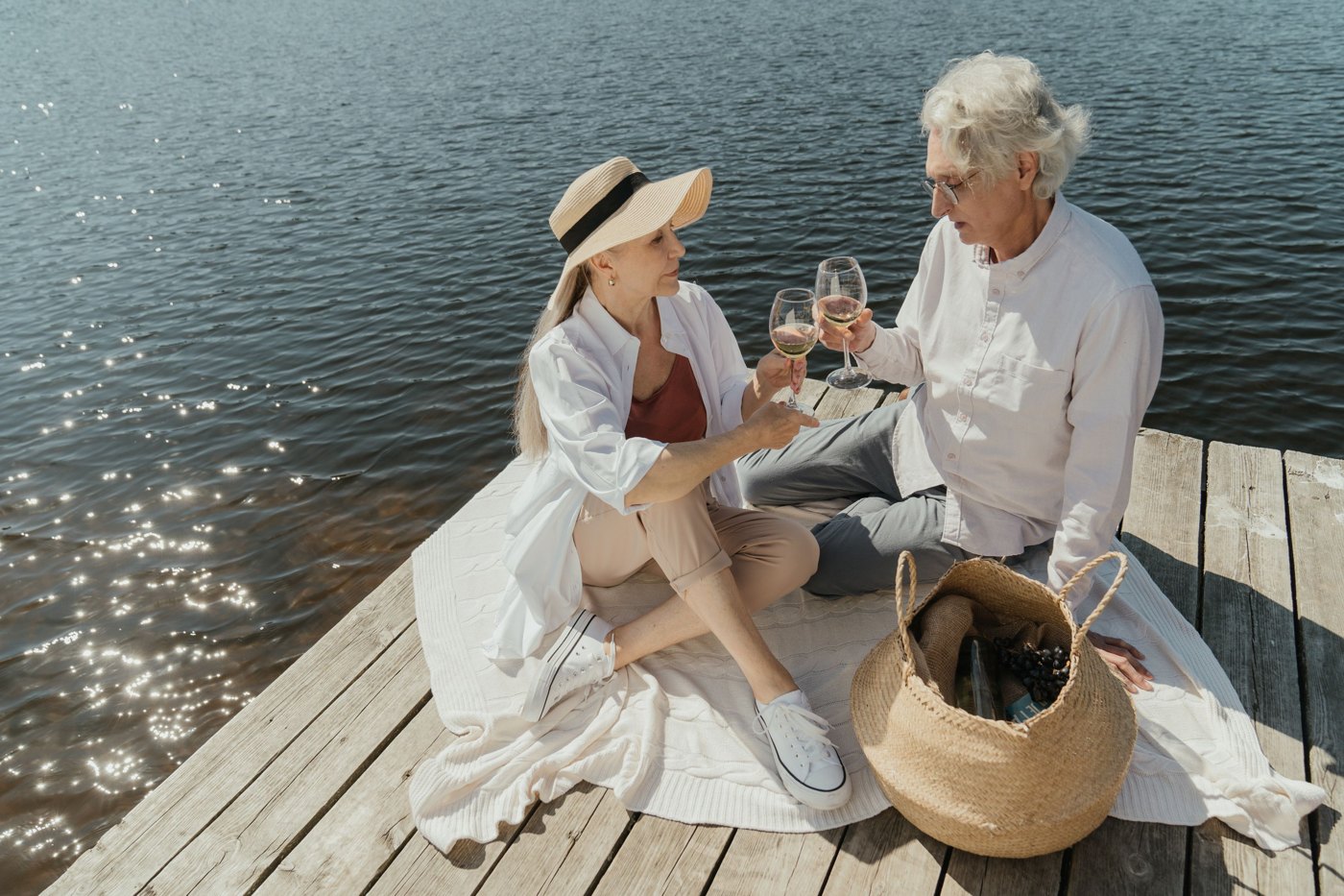Un couple de seniors partage un pique-nique près de l’eau.